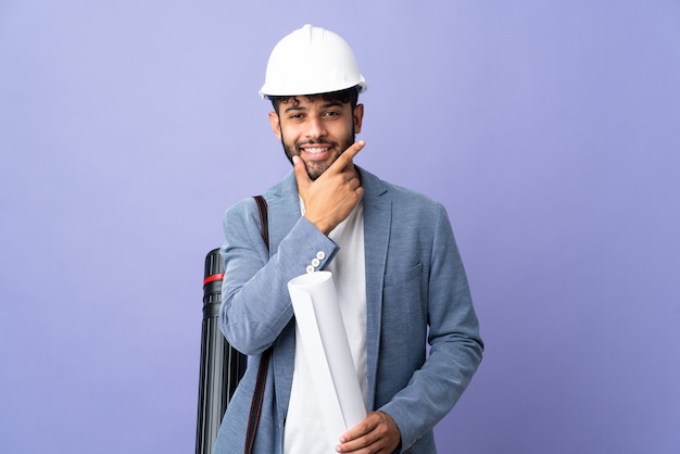 Jovem arquiteto marroquino com capacete e segurando plantas feliz e sorridente