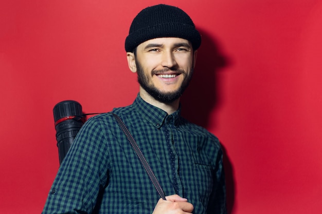 jovem arquiteto moderno, sorrindo homem carregando desenho tubo isolado na parede vermelha.