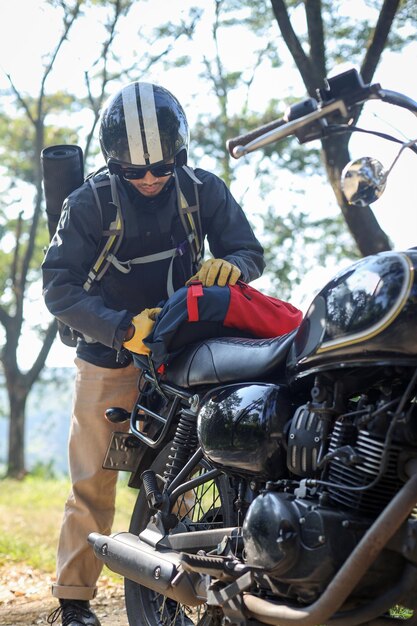 Foto jovem arruma sua mala em sua moto se preparando para passeios de aventura