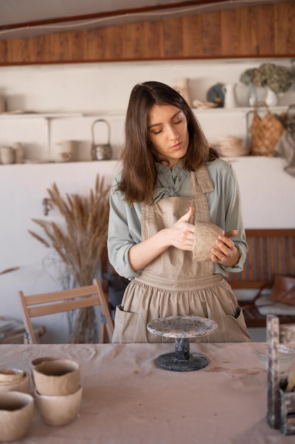 jovem artesã focada na escultura de uma tigela de barro bruto durante uma aula de cerâmica ou oficina em um estúdio criativo Mulher proprietária de uma empresa de cerâmica fazendo artesanato para venda em uma loja de cerâmica feita à mão