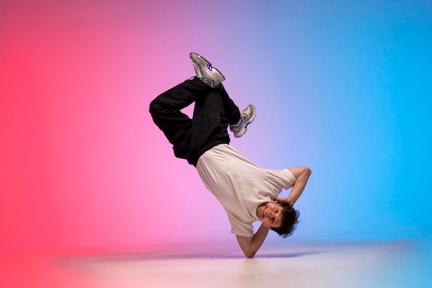 Jovem artista de hip-hop a dançar break dance na iluminação do clube de néon e a fazer truques acrobáticos