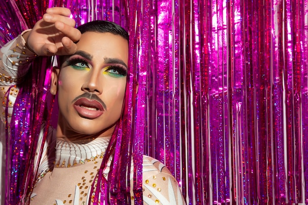 Jovem artista de maquiagem drag queen com fundo colorido