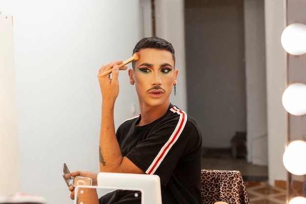 Jovem artista drag queen fazendo maquiagem no camarim