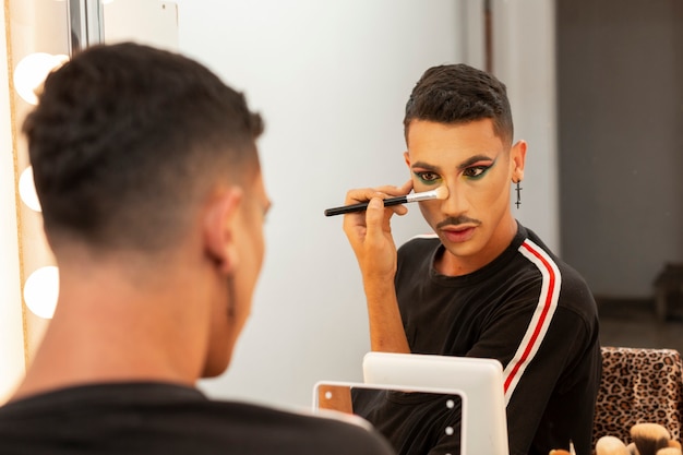 Foto jovem artista drag queen fazendo maquiagem no camarim