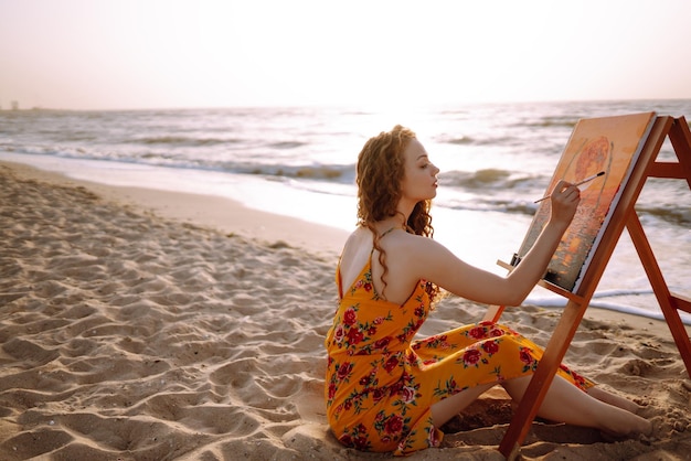 Jovem artista feminina desenhando a imagem na praia hobby e conceito de lazer