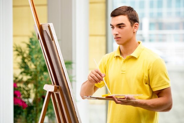 Jovem artista masculino desenhando em estúdio brilhante