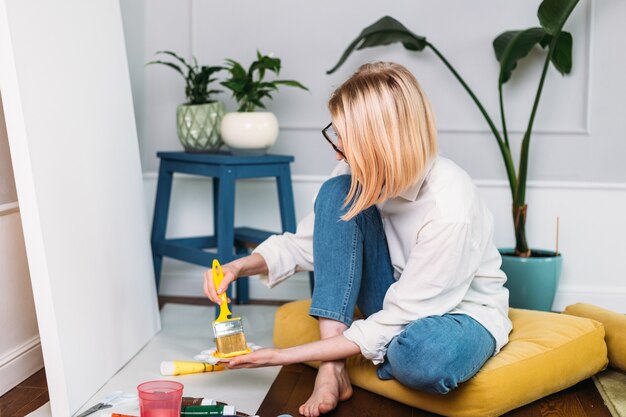 Jovem artista pintando em casa em um estúdio criativo