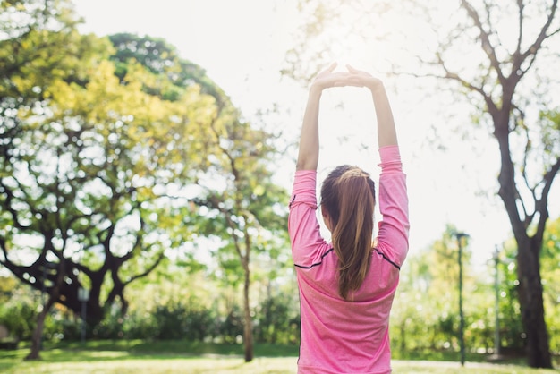 Jovem asiática aquece o corpo esticando antes do exercício matinal e yoga no parque