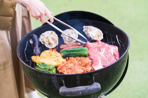 Jovem asiática assando ingredientes no churrasco