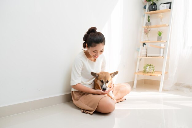 Jovem asiática atraente com seu cachorro Corgi em casa