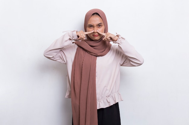 Jovem asiática bonita muçulmana segurando o nariz por causa de um cheiro ruim