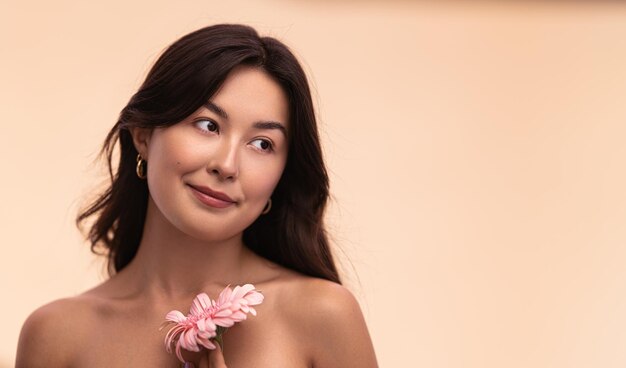 Foto jovem asiática com flor de gerbera durante uma sessão de spa