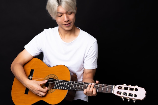 Jovem asiática com guitarra sobre fundo preto