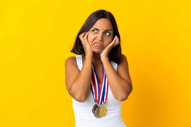 Jovem asiática com medalhas isoladas no fundo branco frustrada e cobrindo as orelhas