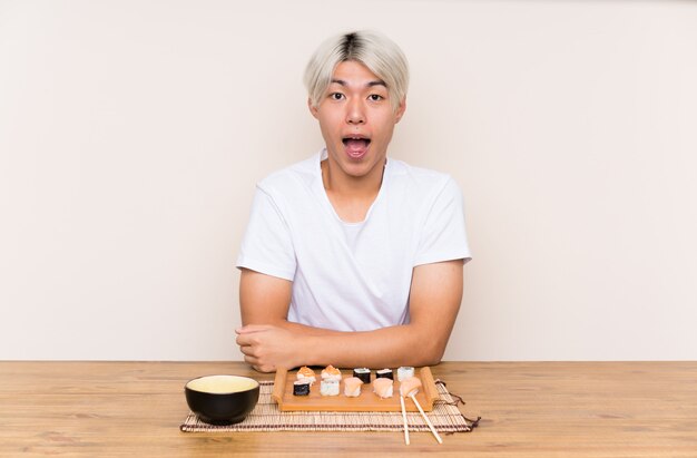 Jovem asiática com sushi em uma mesa com expressão facial de surpresa