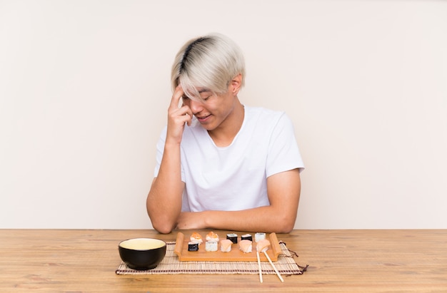 Jovem asiática com sushi em uma mesa rindo