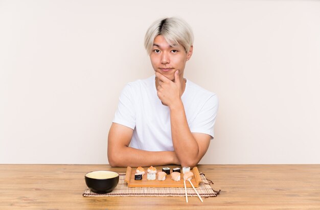 Jovem asiática com sushi em uma mesa rindo