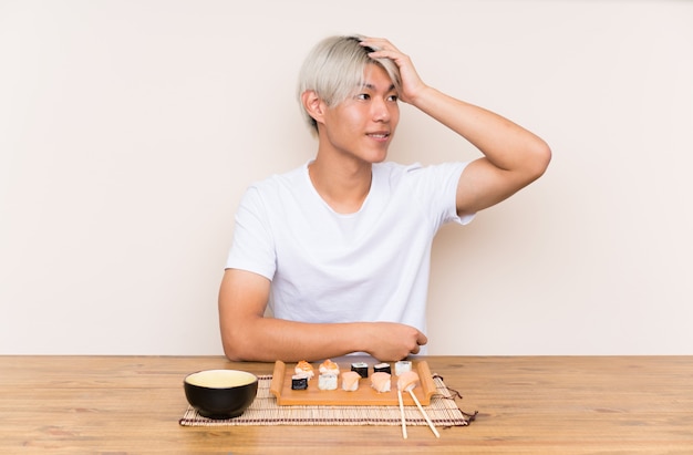 Jovem asiática com sushi em uma mesa rindo