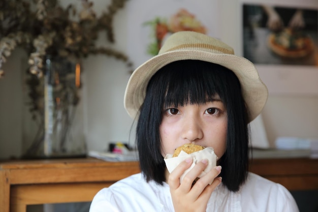 Jovem asiática comendo biscoito em uma cafeteria