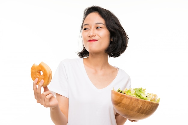 Jovem asiática isolada sobre com salada e rosquinha