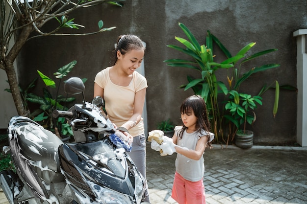 Jovem asiática lavando uma motocicleta