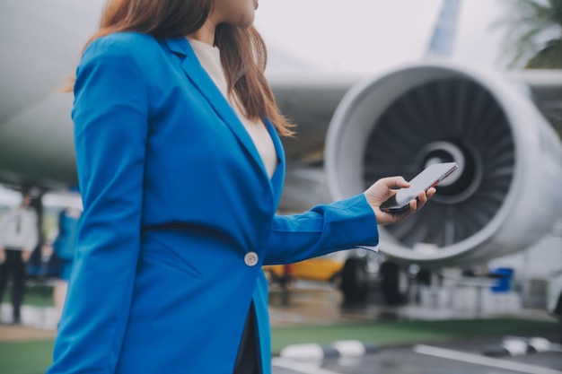 Foto jovem asiática no aeroporto internacional usando um smartphone móvel e verificando o voo no quadro de informações de voo