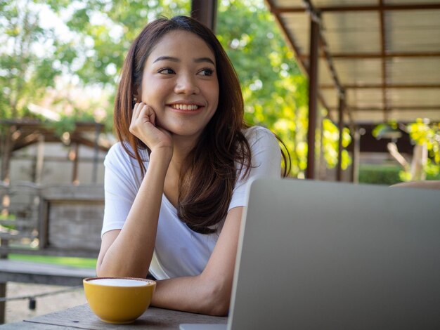 Jovem asiática ou escritora sentada em um diário ou escrevendo um romance em um café fora do escritório Mulheres freelance estão relaxando escrevendo trabalhos Mulheres asiáticas mulheres bonitas Escritoras