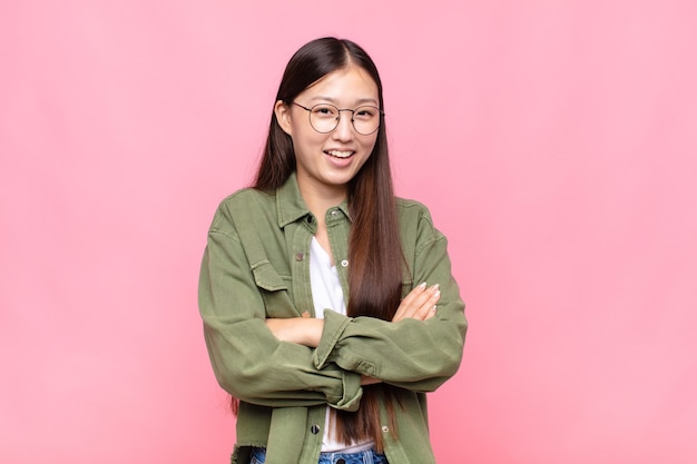 Jovem asiática parecendo uma empreendedora feliz, orgulhosa e satisfeita, sorrindo com os braços cruzados