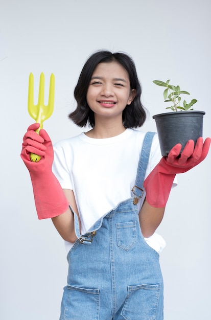 Jovem asiática plantando uma flor, usar jeans e camisa branca com um rosto sorridente