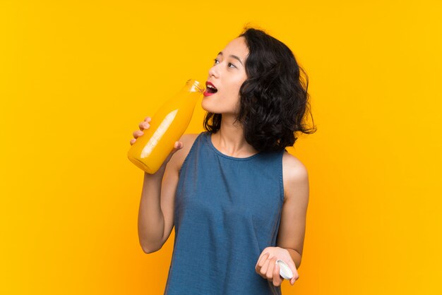 Jovem asiática segurando um suco de laranja