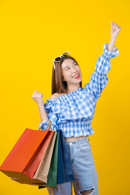 Jovem asiática sorridente e atraente carregando uma sacola coloful de compras