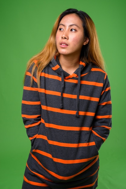 Foto jovem asiática vestindo um moletom contra um espaço verde