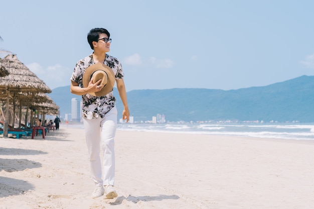 Jovem asiático caminhando na praia