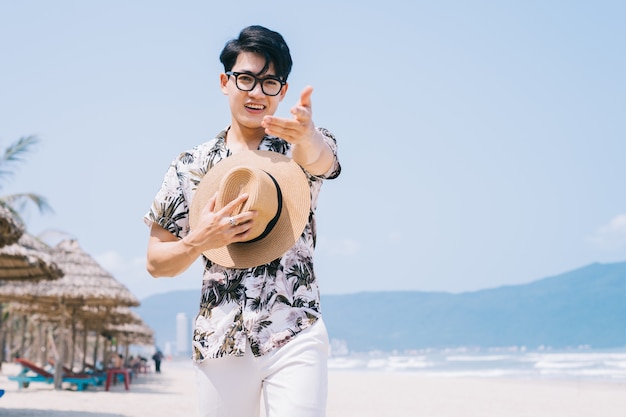 Jovem asiático caminhando na praia