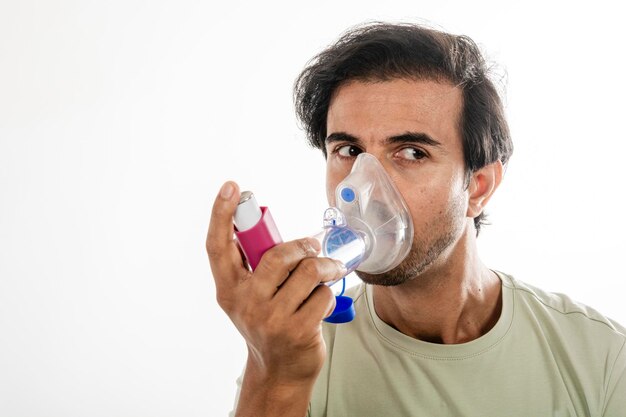 Foto jovem asiático da índia usando um inalador respiratório tiro de estudo em fundo branco foco seletivo