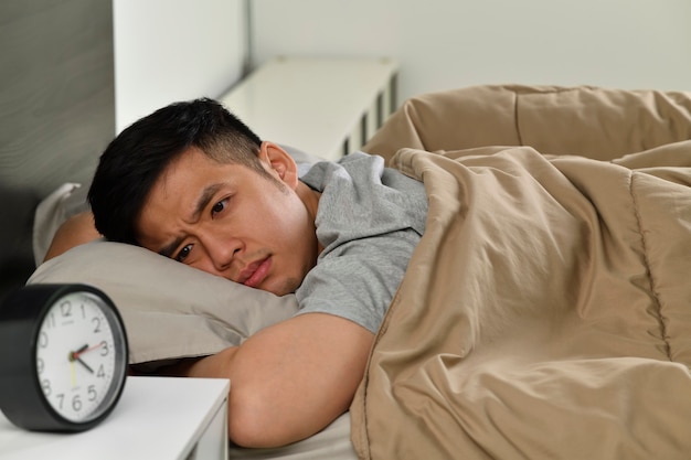 Foto jovem asiático deprimido deitado na cama não consegue dormir de insônia