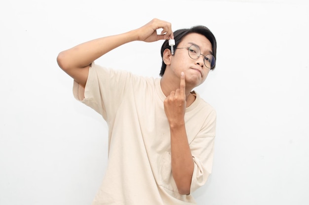 jovem asiático em camiseta bege casual aplicando soro de acne de beleza usando pipeta