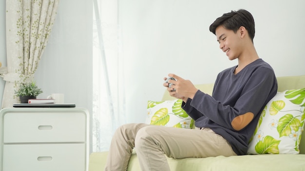 Jovem asiático jogando no smartphone em casa