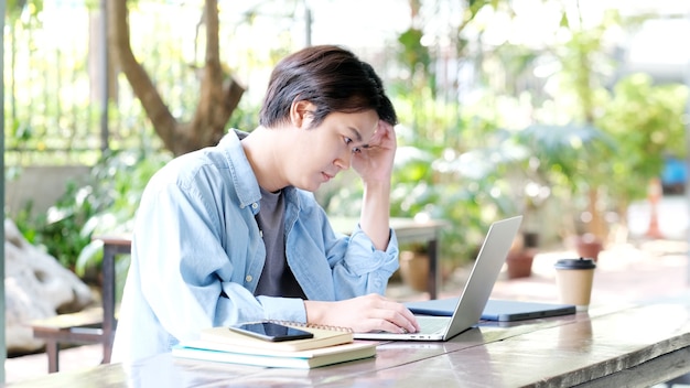 Jovem asiático lutando com um laptop Estudo online frustrado de estudante da Ásia