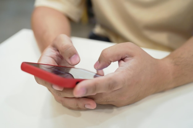 Jovem asiático relaxado usando telefone inteligente, gastando tempo verificando notícias nas mídias sociais