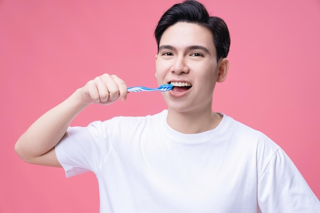 Jovem asiático segurando a escova de dentes no fundo