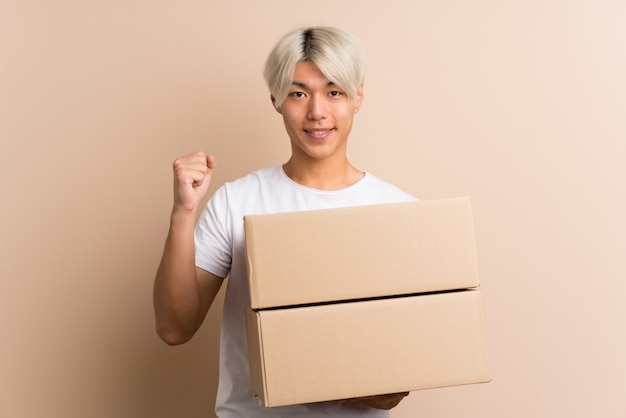 Jovem asiático segurando uma caixa para movê-lo para outro site