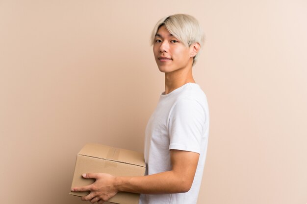 Jovem asiático segurando uma caixa para movê-lo para outro site