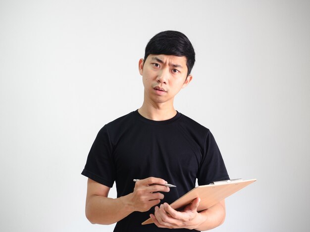 Jovem asiático segurando uma prancheta de madeira e uma caneta de prata na mão com uma cara séria no fundo branco