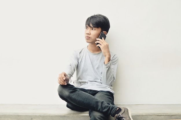 Jovem asiático sentado a falar ao telefone