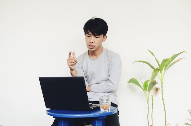 Jovem asiático sentado em frente ao laptop com uma cara sombria