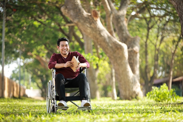 Jovem asiático sentado na cadeira de rodas no hospital do parque