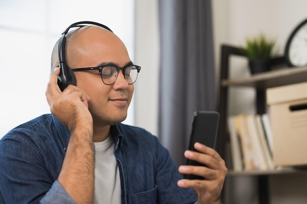 Jovem asiático usando fone de ouvido e ouça a música do smartphone