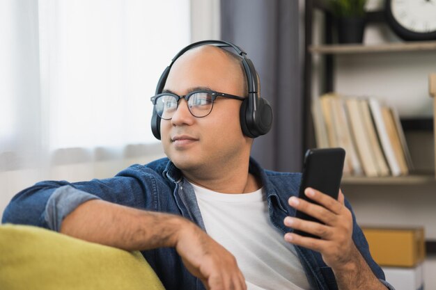 Jovem asiático usando fone de ouvido e ouça a música do smartphone