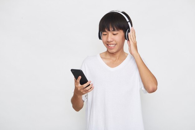 Jovem asiático usando fones de ouvido de um smartphone em branco